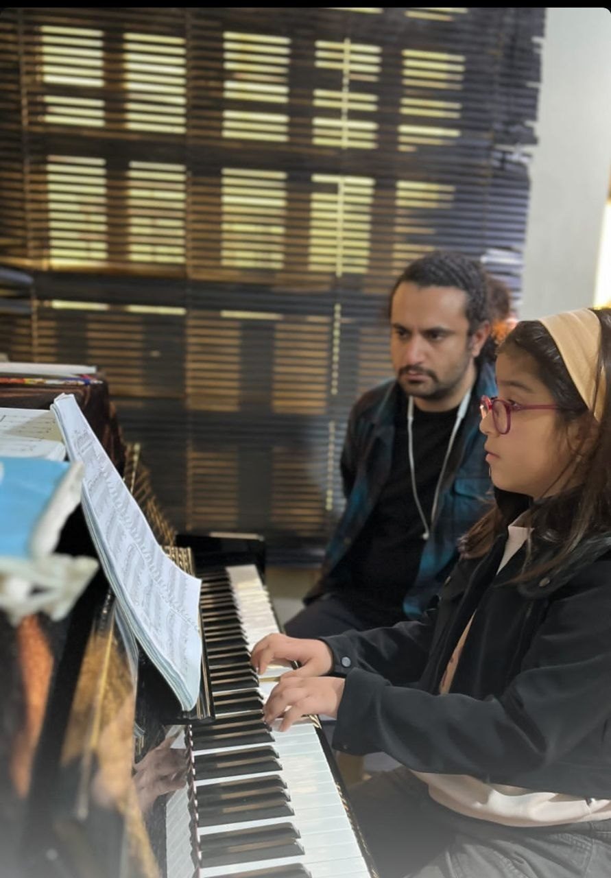 Mohammadali Rezaei teaching a young pianist at an upright piano