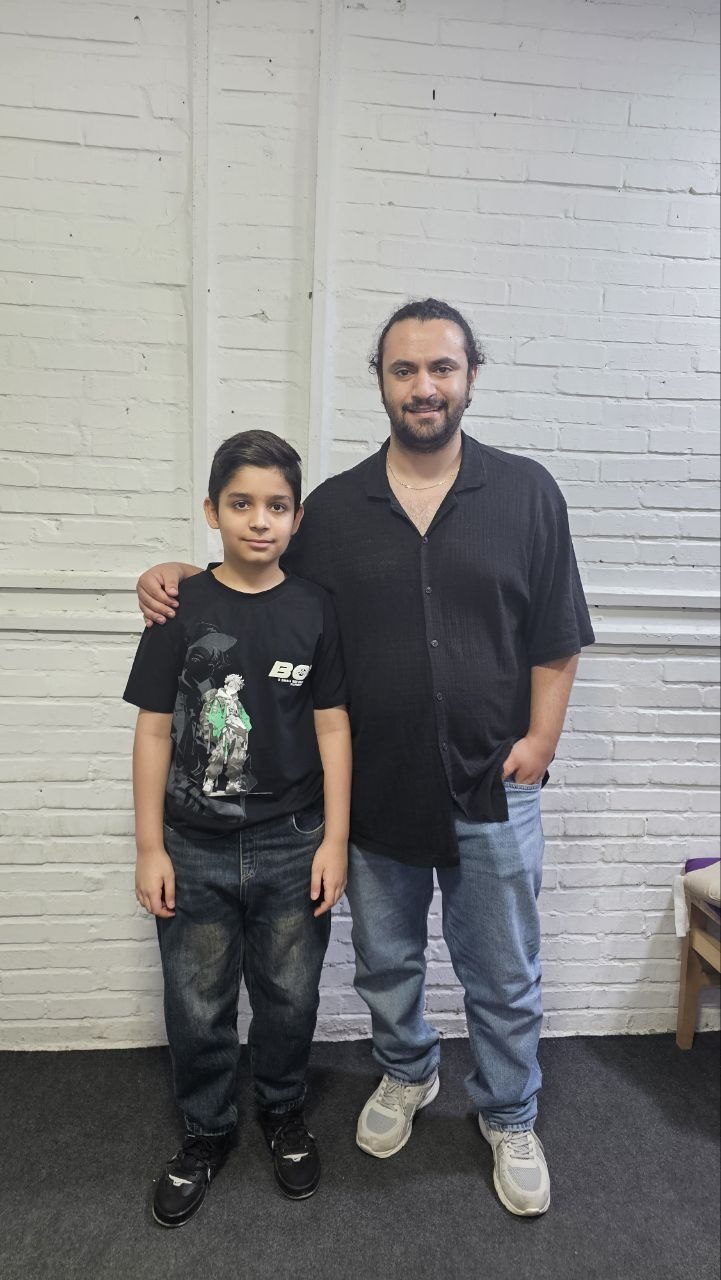 Mohammadali Rezaei, pianist, composer and piano teacher, standing with a young student